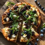 Sweet-savory Blueberry, Feta, and Honey-Caramelized Onion Naan Pizza on a wooden board.