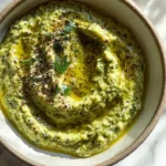 Vibrant green vegan zucchini dip in a bowl, garnished with zaatar and olive oil.