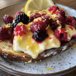 A slice of Brie Toast with macerated berries and lemon zest.