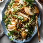 A bowl of Quinoa Salad with apples, arugula, and crispy shallots.