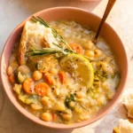 A bowl of golden White Bean and Lemon Soup with rosemary and lemon.