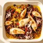 A baking dish of golden Baked Stuffed Squid with aubergine and peppers.