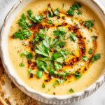 A bowl of golden Garlic Potato Soup with fresh chives and truffle oil.